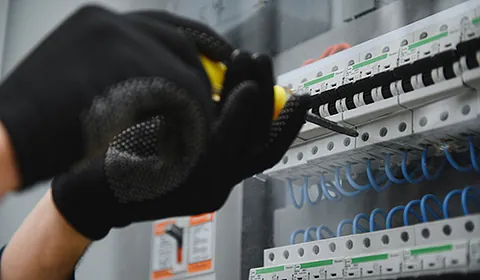 Eine Person in Handschuhen arbeitet an einer Schaltung. 