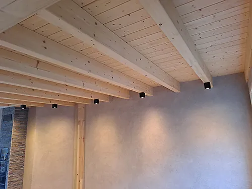 Gemütlich beleuchteter Raum mit sichtbaren Holzträgern und einer Holzdecke.